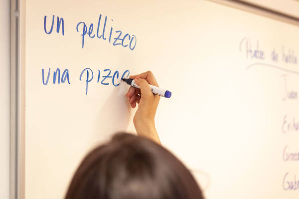 Person schreibt spanische Wörter an die Tafel