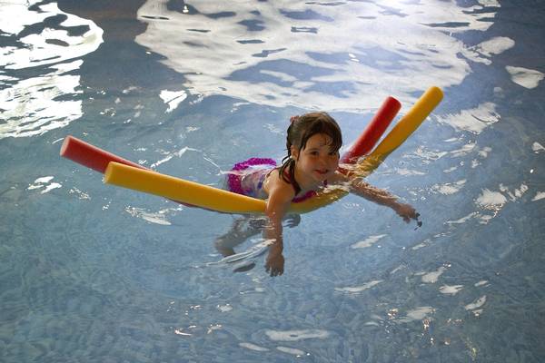 Kind mit Schwimmnudel im Wasser