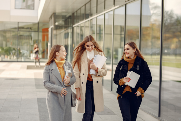 drei junge Frauen spazieren vor der Uni